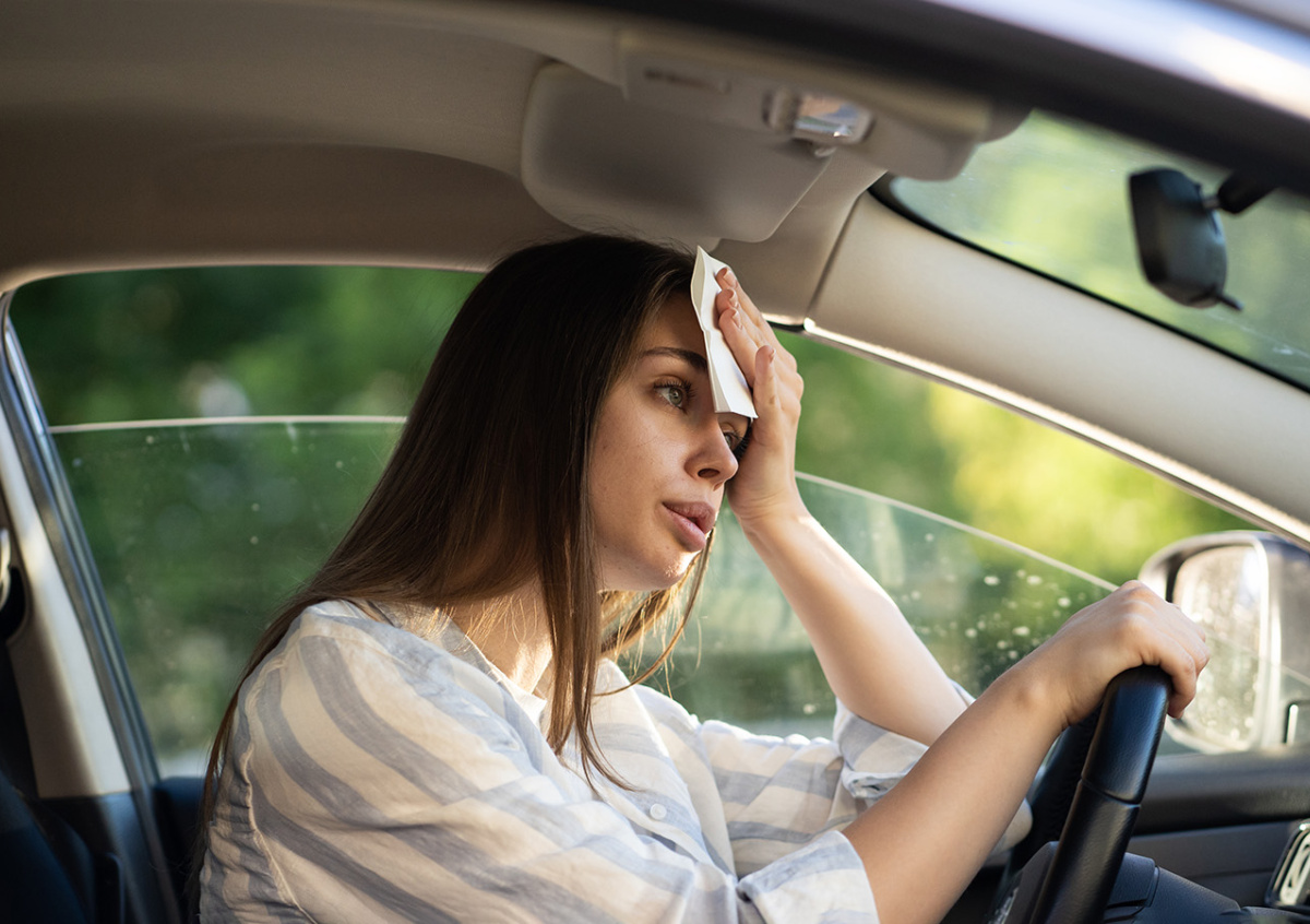 Driver wiping sweat inside a hot car